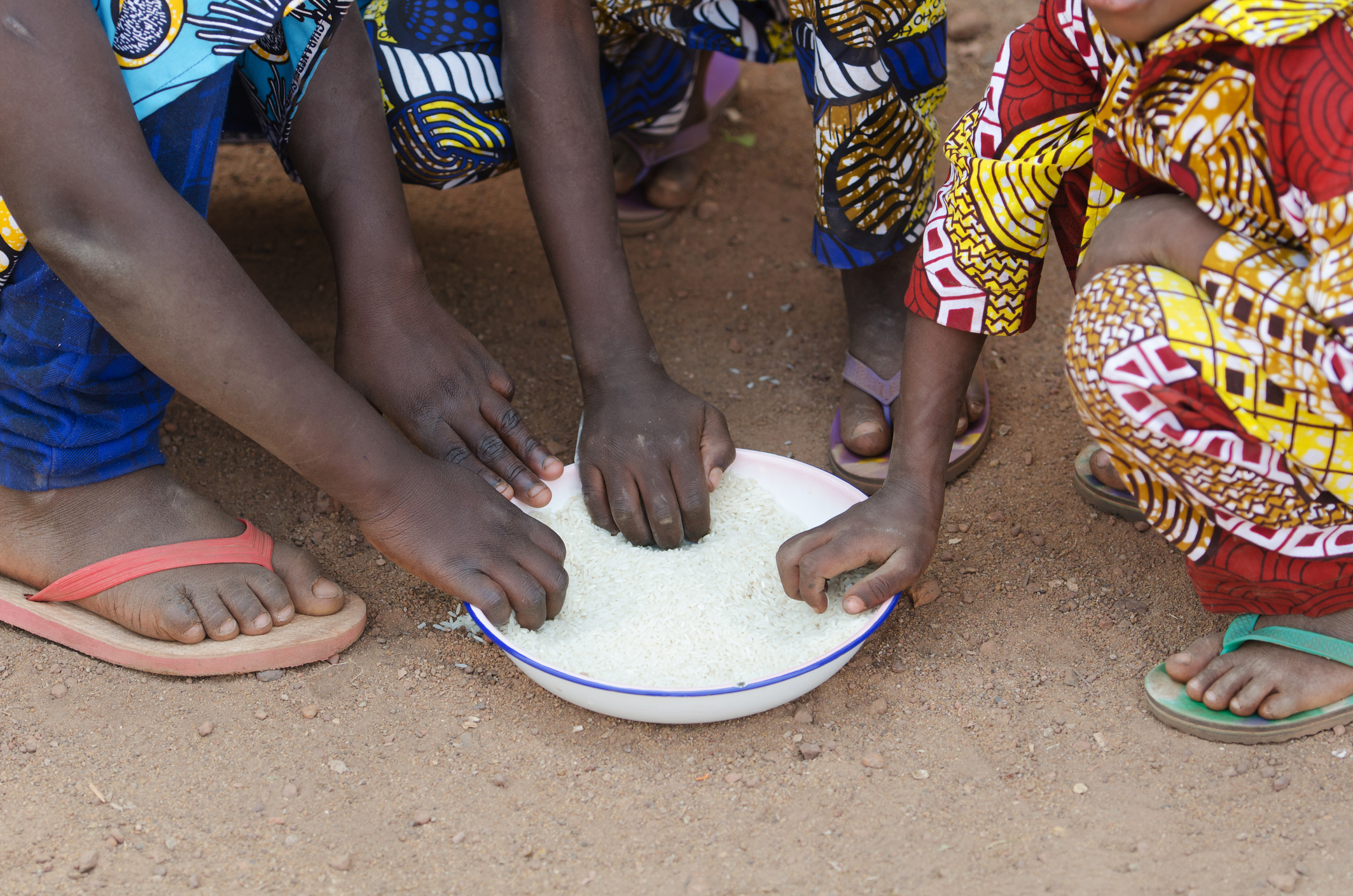 Close-up of young African boys and girls sharing a meal outdoors. This image illustrates the importance of food safety solutions and contamination prevention for healthy childhood development.