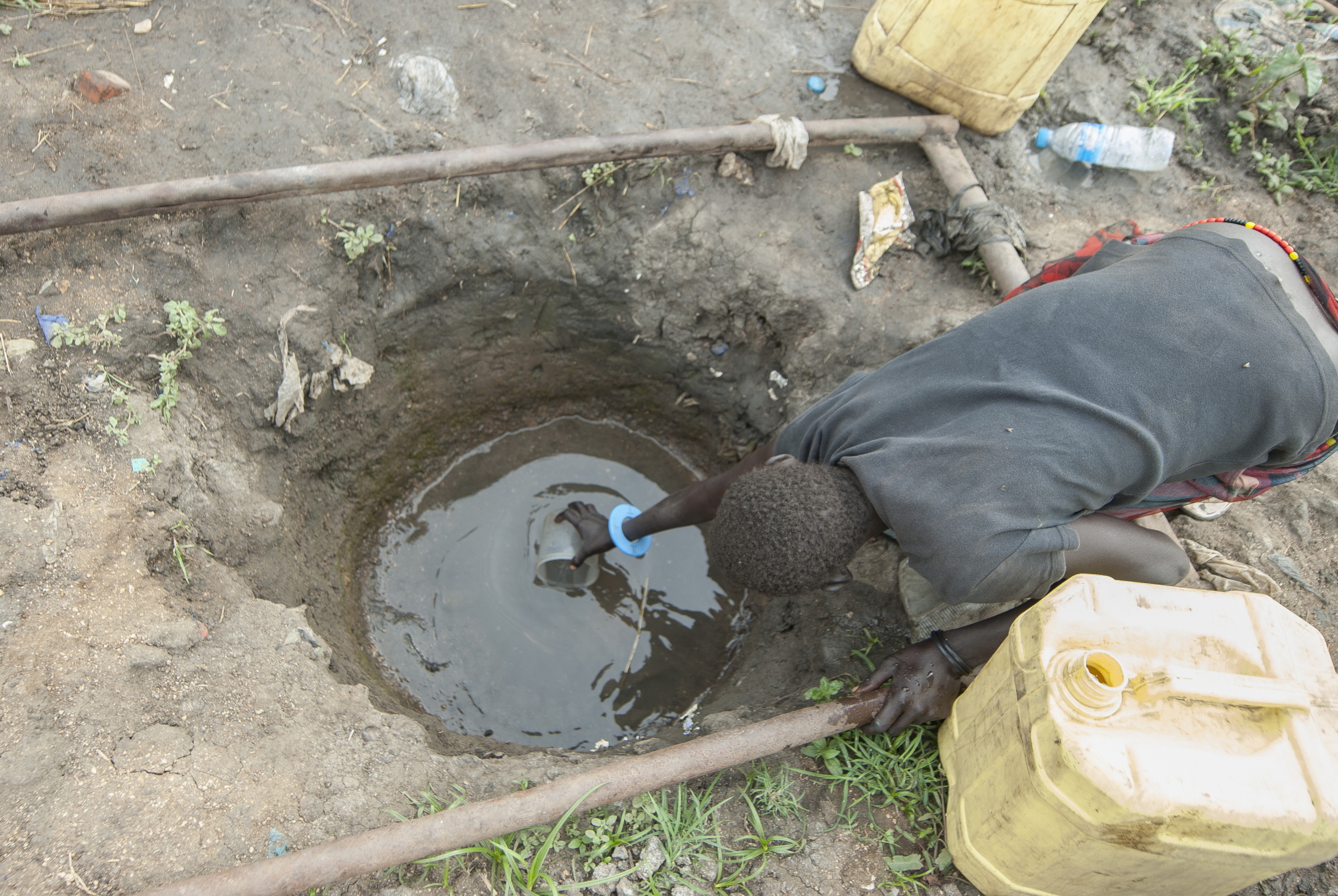 Woman in South Sudan refugee camp drinking from dirty water hole